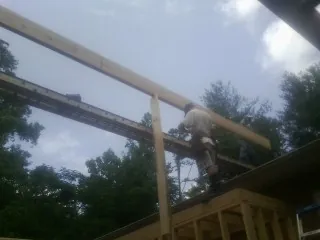 Carpenter setting a ridge beam over a new addition frame — Ice Dam Removal by Roofing Brothers in Charles City