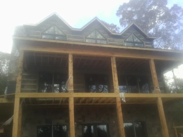 Dormers and porch framing on a large log home under construction — Roof Coating work by our crew in Charles City