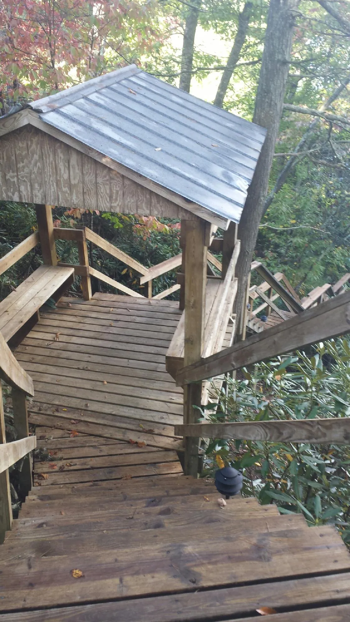 Metal roofed shelter over wooden steps on a wooded walkway — Skylight Repair & Installation work by our crew in Charles City