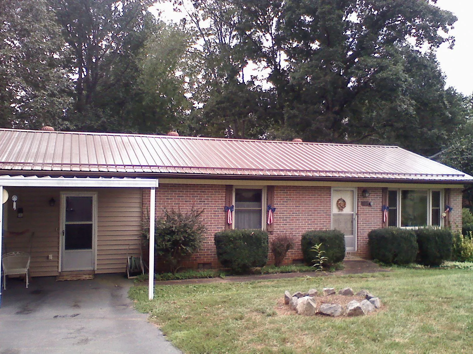 Bronze metal roof and carport on a brick ranch home — Roof Repair work by our crew in Charles City